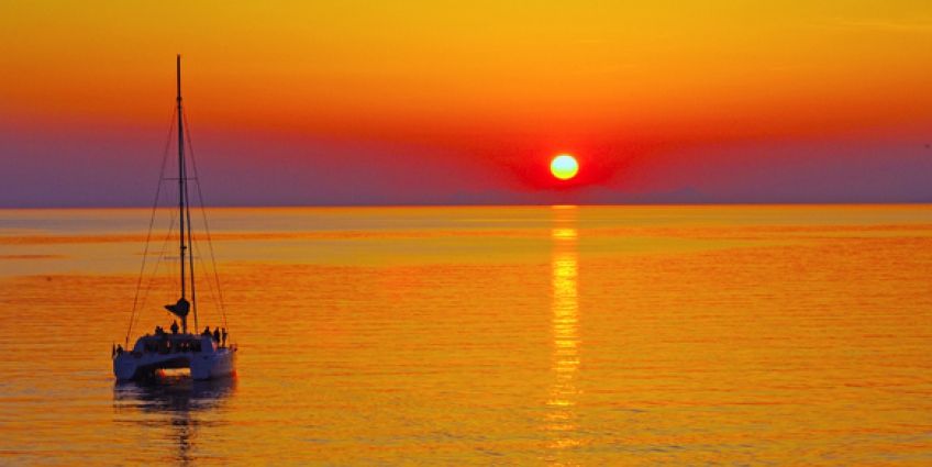 Boat sailing on sea in Santorini at sunset