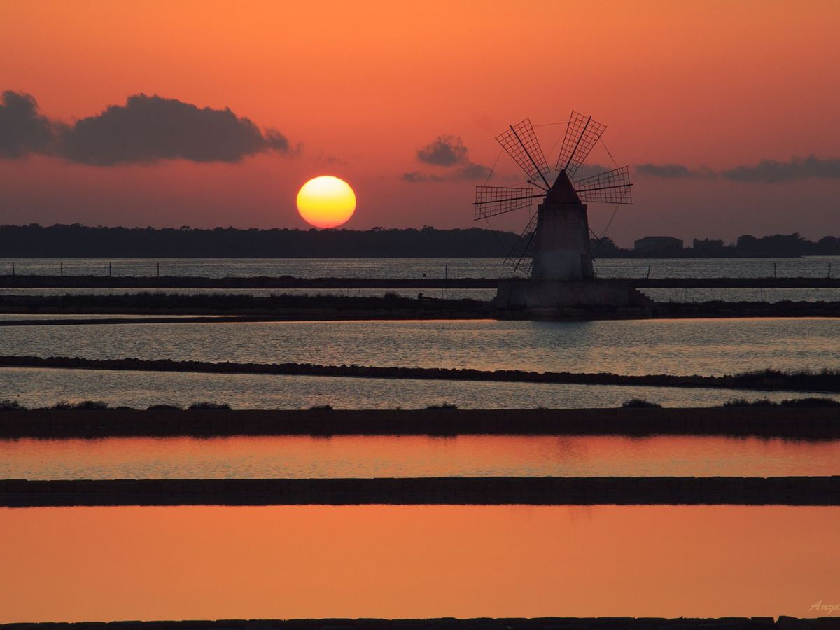 Sunset over Saline di Trapani, in Sicily, with windmill in the background.
